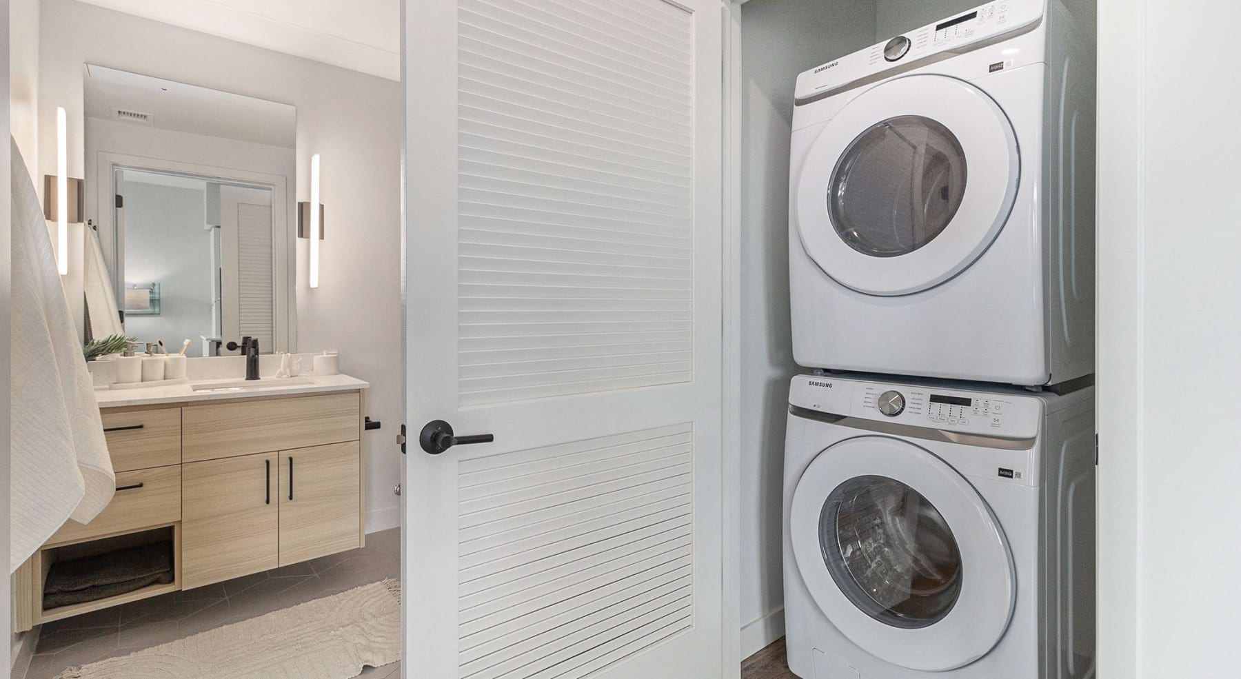 a laundry closet with a stackable washer and dryer near a bathroom