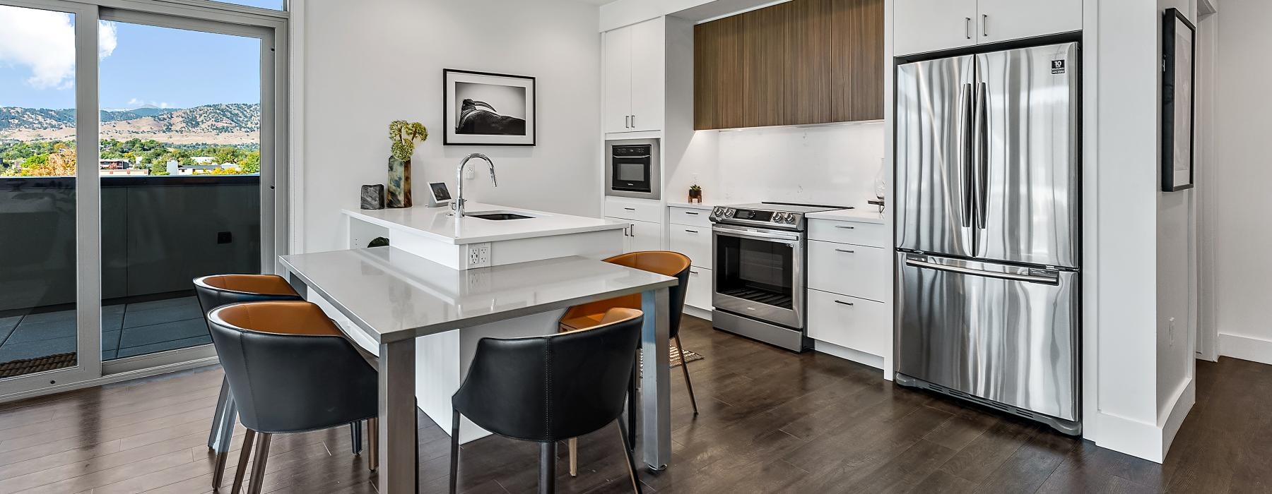 Model living room at our Boulder, CO luxury apartments for rent, featuring wood grain floor paneling and a kitchen island. 